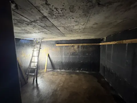Concrete cistern drained and cleaned, with wood strapping installed along the top of the wall