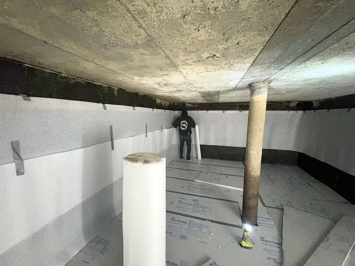 Cistern liner installation: Rigid foam boards cover the floor, wall foam hangs from the strapping and the column is wrapped.