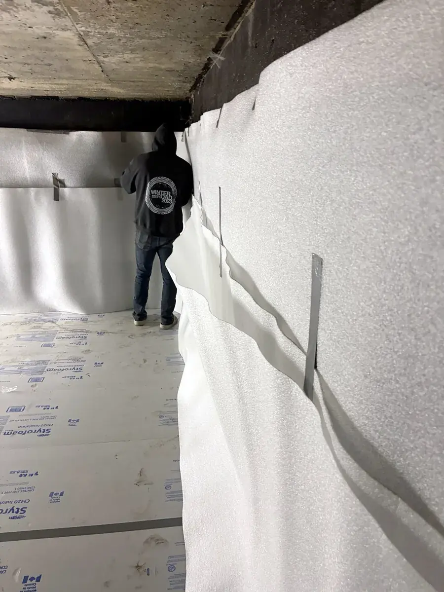 Cistern liner installation: Overlapped wall seam with temporary tape tabs.