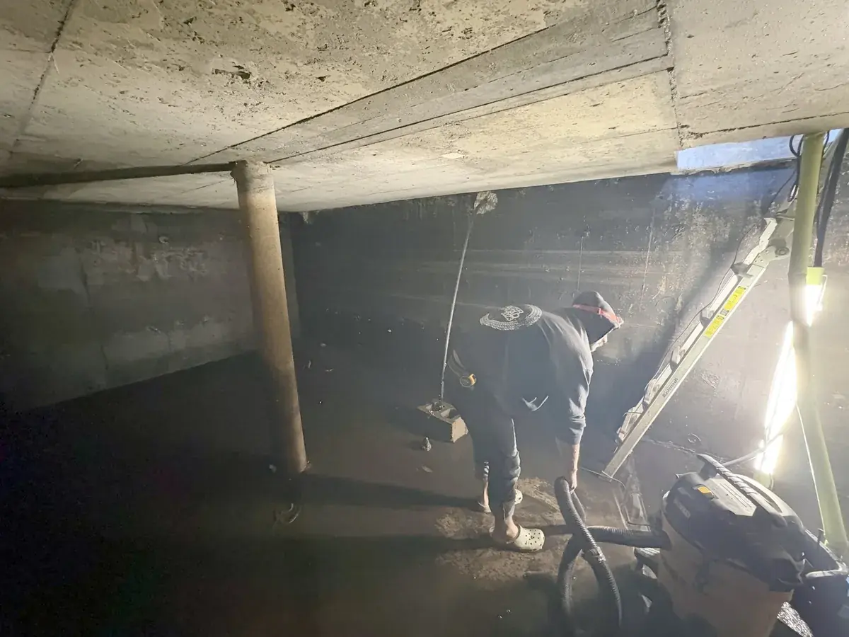 Cistern liner installation: Wet/dry vac removing the last water and sludge from the floor.